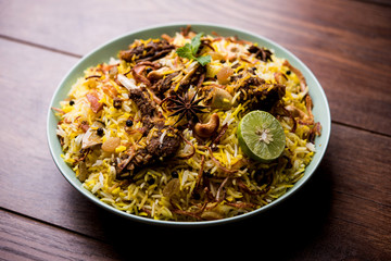 mutton or lamb biriyani with basmati rice, served in a bowl over moody background.