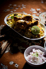Delicious spicy chicken biryani in bowl over moody background, it’s a popular Indian and Pakistani food.