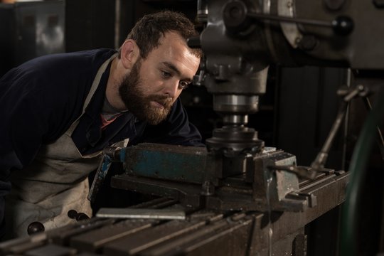 Blacksmith using press drill in workshop