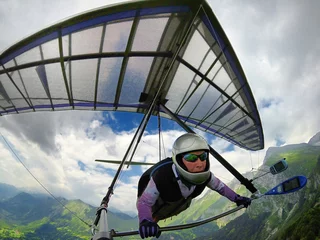 Foto op Plexiglas Aerial shot of brave extreme hang glider pilot soaring the thermal updrafts above mountains © Mny-Jhee