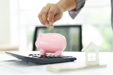hand putting coin money to piggy bank saving, save money concept.Real estate sale, home savings, loans market concept.