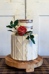 Elegant 2 tier wedding cake with edible floral arrangement. Cake has knitted and naked design and edible rose flower.