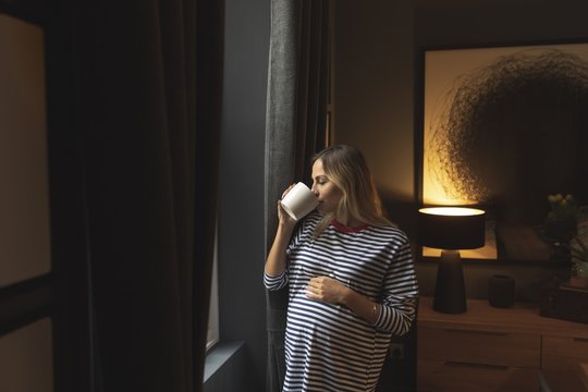 Pregnant young woman with bleached hair drinking coffee