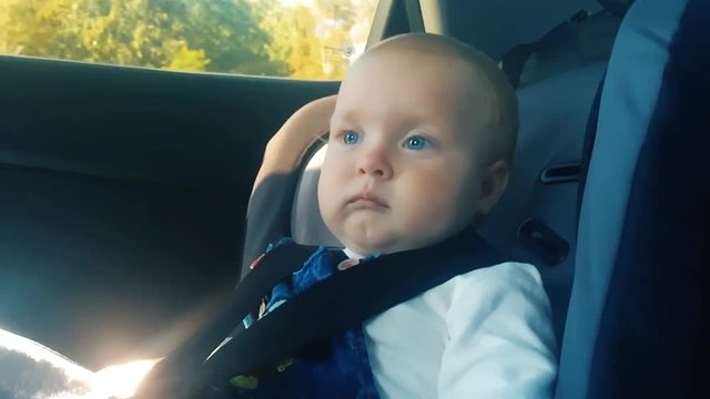 Baby Kid In The Children's Car Seat In The Car Rides. Little Baby Kid In An Automobile Armchair