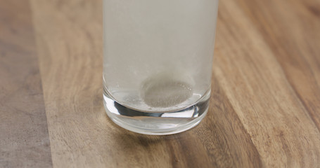 effervescent tablet in glass of water on wood table