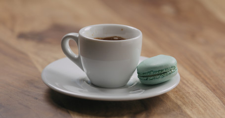 light blue macaron on saucer with coffee cup