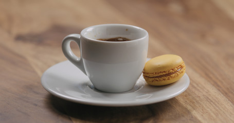orange macaron on saucer with coffee cup