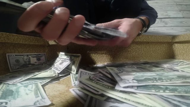 Men packing dollar bills in to briefcase