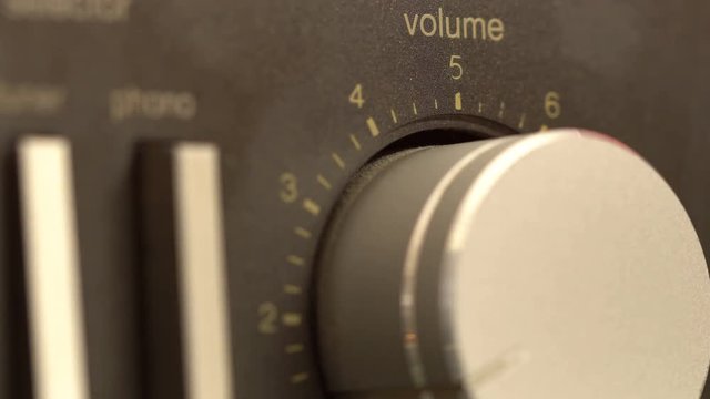 Volume knob turning up and down, fingers shot close up adjusting volume on a classic hi-fi stereo receiver