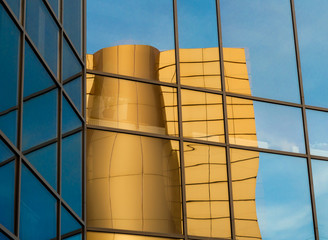 distorted reflection of a yellow building in the mirrored windows of an office building