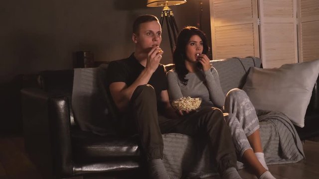 Young couple watching horror on tv at home. Reacting on screamer