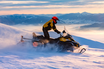 Fototapeta na wymiar A man is ridind snowmobile in mountains.