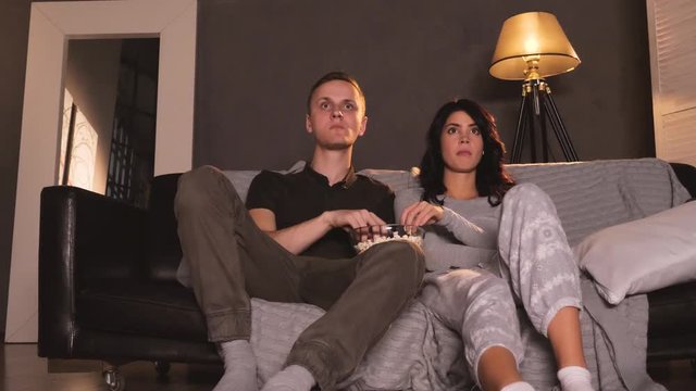 Young couple watching horror on tv at home. Reacting on screamer