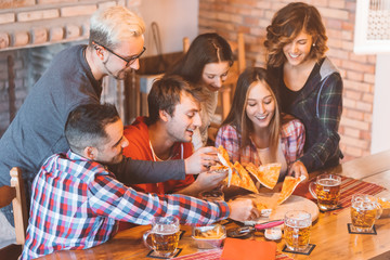 Group of young people having fun, eating pizza and drinking beer together - teenagers friends...