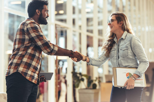 Happy business partners greeting each other at a meeting