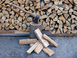 Dry oak firewood stacked in a pile, chopped wood for winter heating of the fireplace. An ax and a...