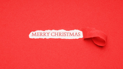 merry christmas greeting seen through hole peeled in red paper background