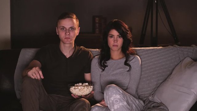 Young couple watching horror on tv at home. Reacting on screamer