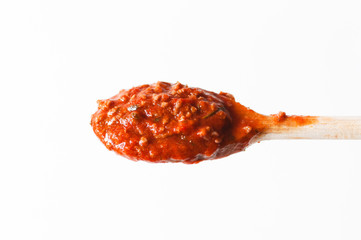 Close up of wooden cooking spoon with homemade traditional Italian pasta sauce made with tomatoes and ground meat, called Ragu alla bolognese typically served with pasta isolated on white background