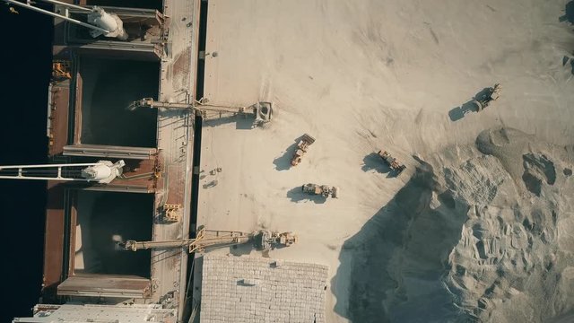 Aerial top down view of bulk carrier ship and cement loaders at seaport