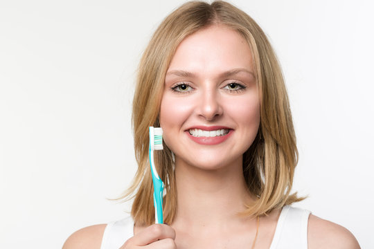 Junge lächelnde Frau hält eine Zahnbürste