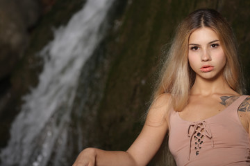 Woman portrait in skin colored swimwear near the waterfall