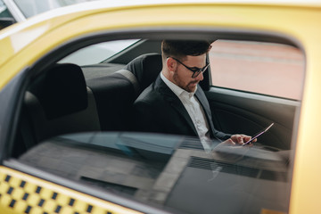 Businessman sitting in cab using his mobile phone