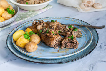 Beef roulade staffed with mushrooms in creamy mushroom sauce served with boiled baby potatoes