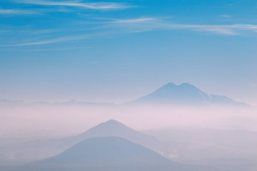 three mountains in the fog on the horizon