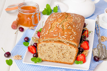 Delicious homemade cake with walnuts and sunflower seeds. Served with fresh berries and honey.