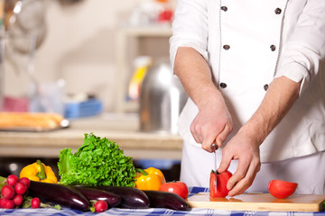 Cook cutting vegetables on the kitchen