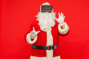 Santa Claus wearing virtual reality goggles, on a red background