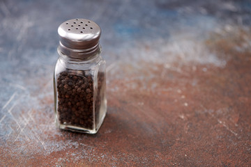 black pepper in the pepper shakers on dark background