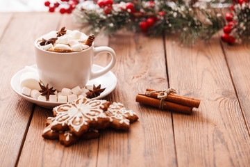 Obraz na płótnie Canvas Christmas or new year background. A Cup of festive hot chocolate or cocoa with marshmallows and traditional handmade gingerbread on the table. The concept of advertising cocoa drink. Copy space