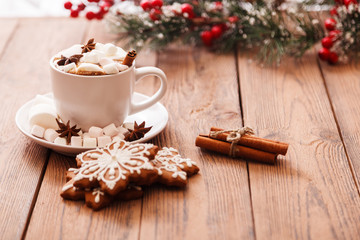 Christmas or new year background. A Cup of festive hot chocolate or cocoa with marshmallows and traditional handmade gingerbread on the table. The concept of advertising cocoa drink. Copy space