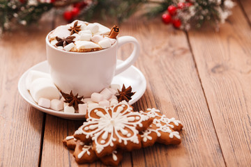 Christmas or new year background. A Cup of festive hot chocolate or cocoa with marshmallows and traditional handmade gingerbread on the table. The concept of advertising cocoa drink. Copy space