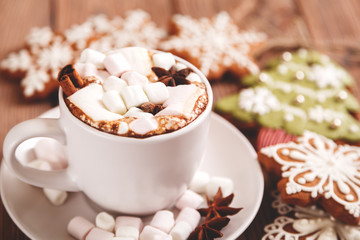Christmas or new year background. A Cup of festive hot chocolate or cocoa with marshmallows and traditional handmade gingerbread on the table. The concept of advertising cocoa drink. 
