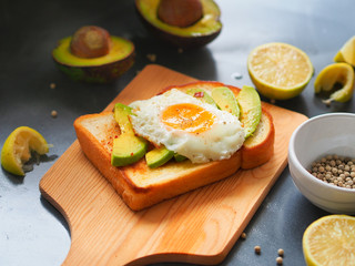 Grilled bread topping with avocado sliced and fried egg on wooden chopping board for healthy  breakfast concept.