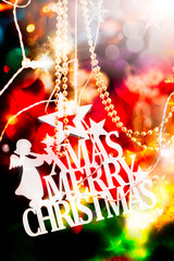 Christmas decoration made with a wooden ornaments with " merry christmas " text and an angel agains a blurred background