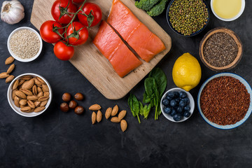 flat lay top-down composition of healthy food concept, salmon, tomatoes, berries, vegetables, chia seeds, nuts, olive oil.