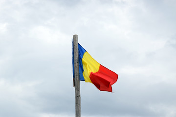 Romanian flag waving in the wind in front of a clean blue sky. Romania National Flag.