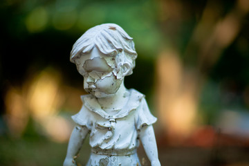 Garden statue of child in corroded condition.