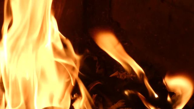 Paper with blurred text burning in fire. Closeup view of red hot glowing flame inside stove. Embers and documents in furnace or campfire.  Abstract background.