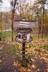 Wooden bird feeder in the autumn park.