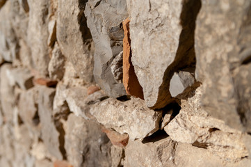 A wall of different grey and light brown angular stones