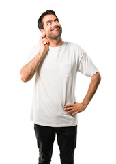 Young man with white shirt standing and thinking an idea while scratching head on isolated white background