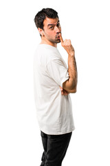 Young man with white shirt showing a sign of closing mouth and silence gesture putting finger in mouth on isolated white background