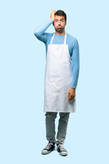 Naklejka premium Full body of Man wearing an apron with an expression of frustration and not understanding. Confused gesturing on blue background