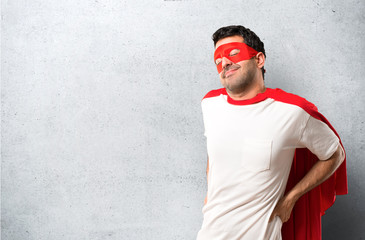 Superhero man with mask and red cape unhappy and suffering from backache for having made an effort...