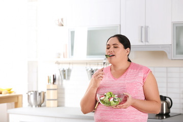 Woman eating vegetable salad in kitchen. Healthy diet